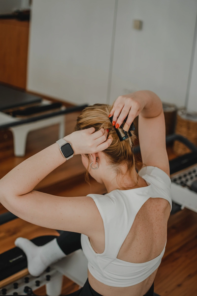 Nő egy fekete csattal feltűzi a haját reformer pilates gyakorlathoz