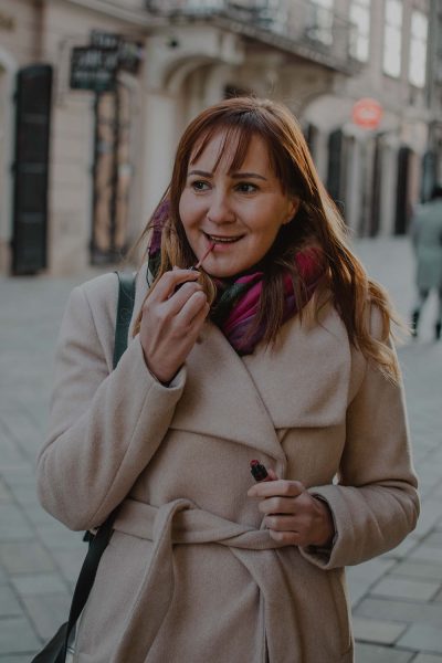 Városi portré fiatal nőről barna hajjal bézs kabátban