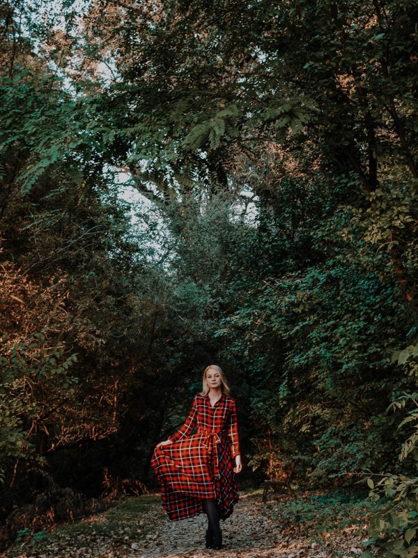 Portré őszi természetben fiatal, szőke, hosszú hajú nőről, piros kockás, hosszú ruhában