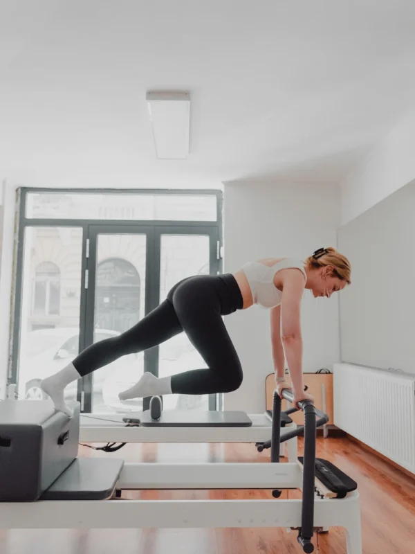 Nő reformer pilates gyakorlatot végez a géptől magát magasba eltolva